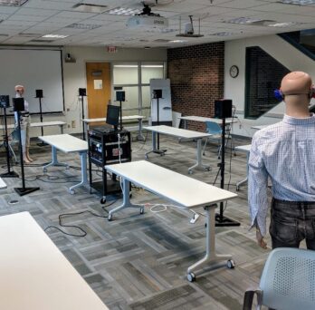 Several mannequins and loudspeakers spread throughout a large room 